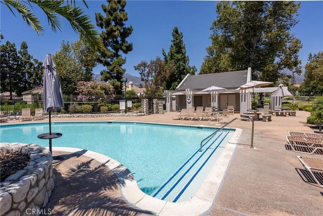 pool with a patio area and fence