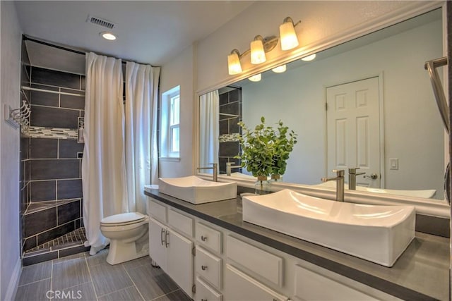 full bath with double vanity, visible vents, toilet, a sink, and tiled shower