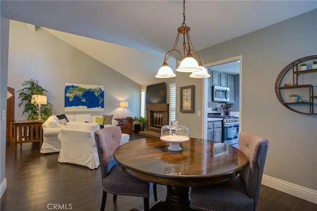 dining space with vaulted ceiling, dark wood-style flooring, a brick fireplace, and baseboards