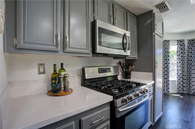 kitchen with appliances with stainless steel finishes, visible vents, dark wood-type flooring, and gray cabinetry