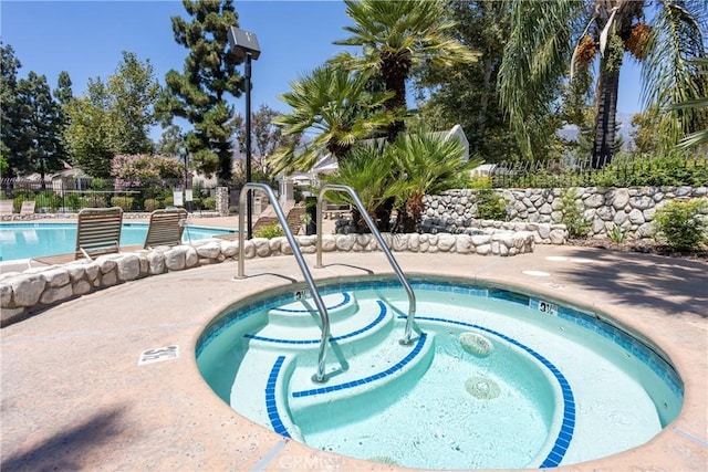 pool with fence and a community hot tub