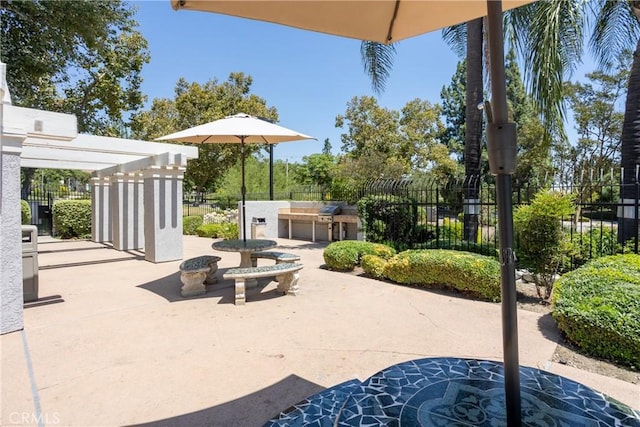 view of patio featuring fence, an outdoor kitchen, and a pergola