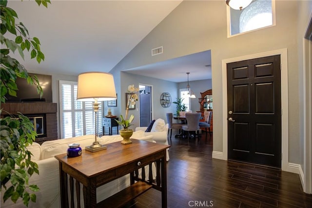 dining space with a brick fireplace, baseboards, visible vents, and dark wood-style flooring