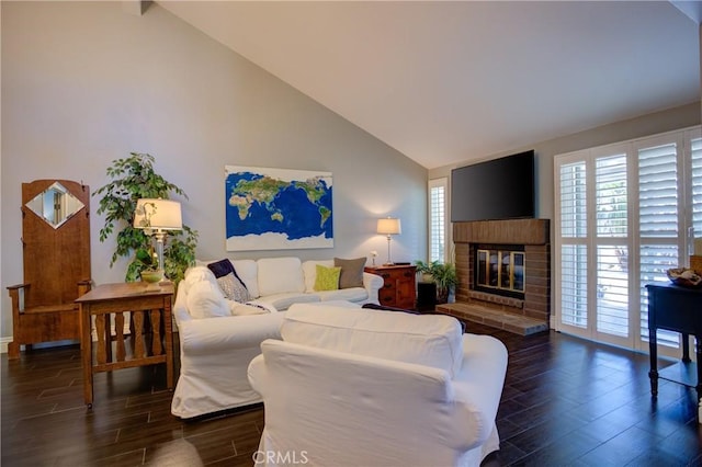 living room featuring high vaulted ceiling, a brick fireplace, and wood finished floors