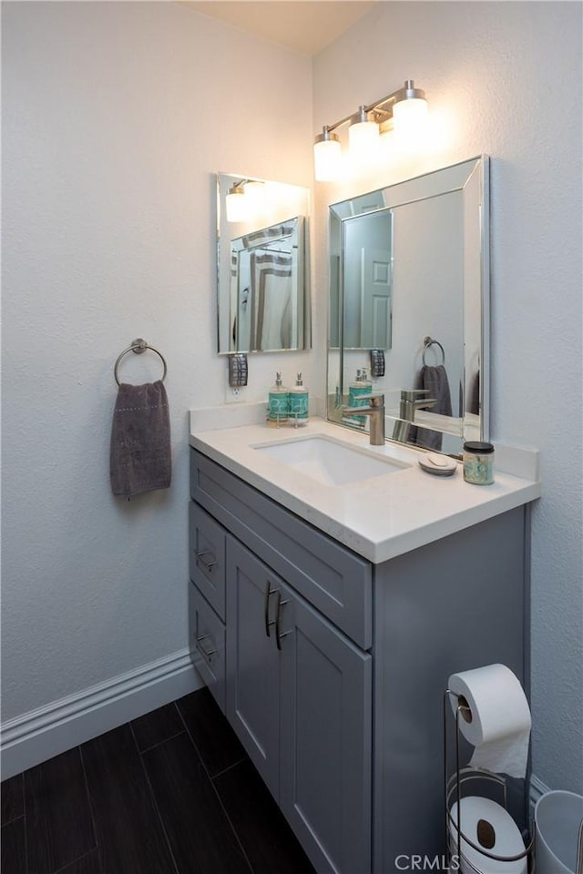 bathroom with wood tiled floor, baseboards, and vanity