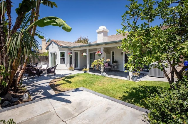 rear view of house featuring a lawn, fence, a patio, and stucco siding