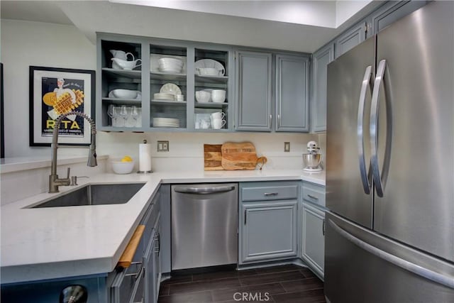 kitchen with wood tiled floor, light countertops, stainless steel appliances, gray cabinetry, and a sink