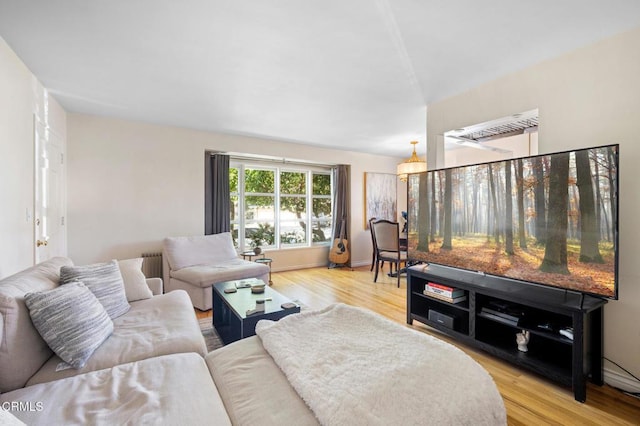 living room featuring light wood-style floors, radiator heating unit, and baseboards