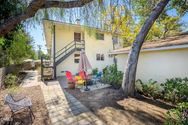 back of house featuring fence, stairs, stucco siding, a chimney, and a patio area