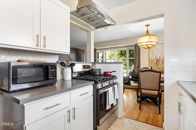 kitchen featuring wall chimney range hood, white cabinetry, and stainless steel appliances