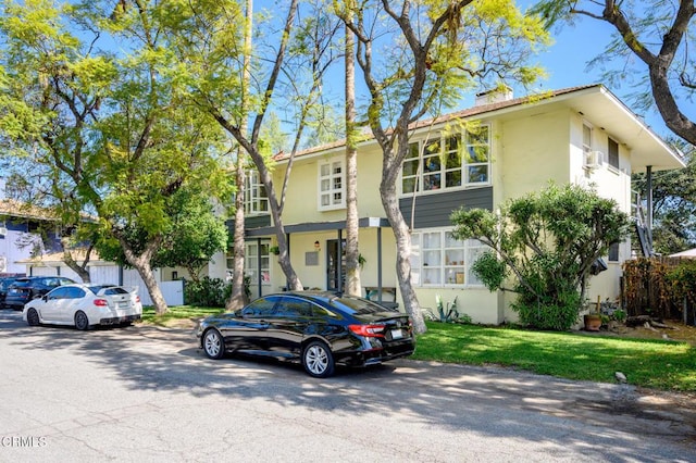 view of property with a front yard, a chimney, and stucco siding