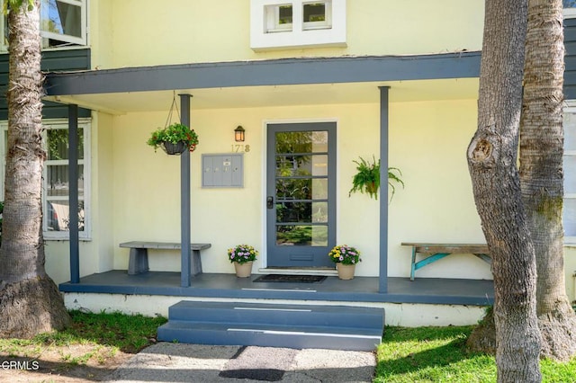 property entrance with covered porch and stucco siding