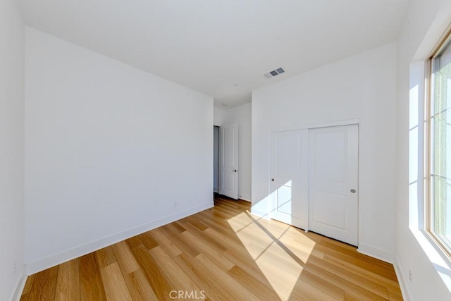 spare room featuring light wood-style flooring, visible vents, and baseboards