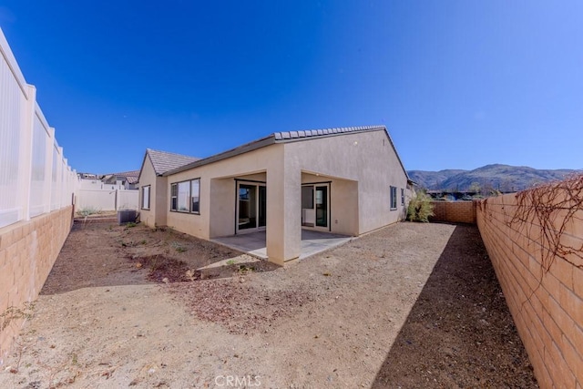 back of house with a mountain view, a fenced backyard, a patio, and stucco siding