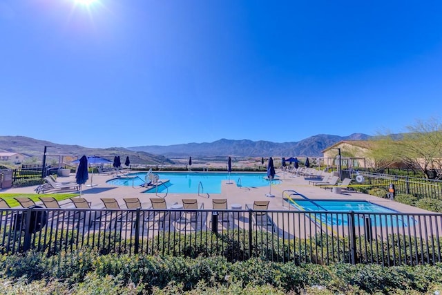 pool with a patio area, fence, and a mountain view