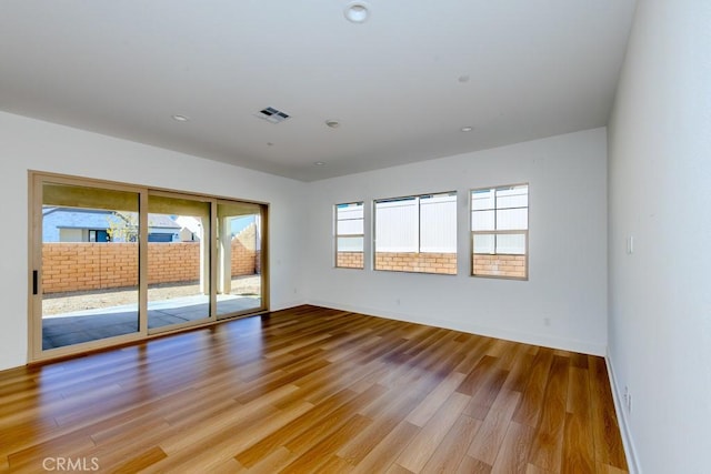 unfurnished room with light wood finished floors, baseboards, and visible vents