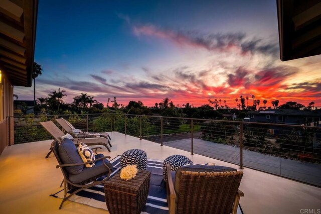 patio terrace at dusk featuring a balcony