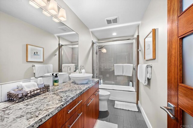 bathroom featuring vanity, visible vents, toilet, shower / bath combination with glass door, and recessed lighting