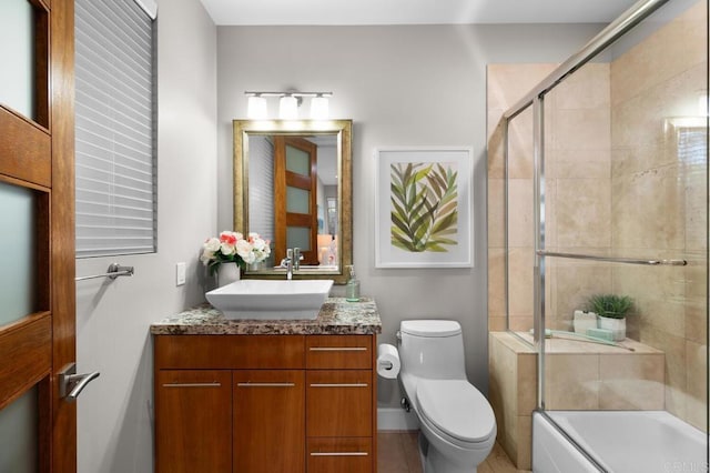 full bath with vanity, toilet, and shower / bath combination with glass door