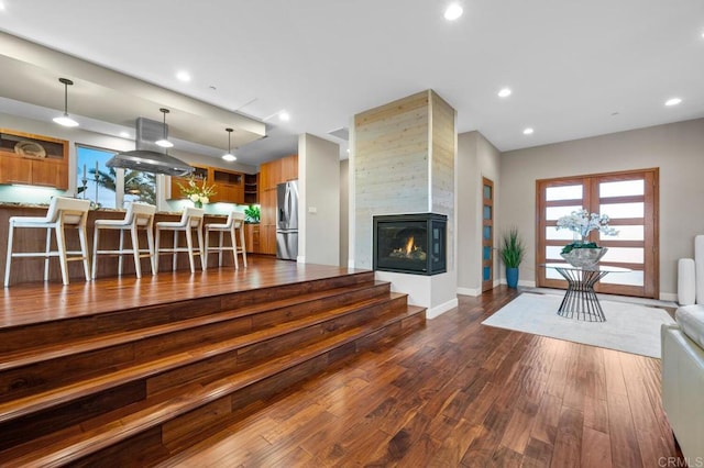 living area featuring a multi sided fireplace, dark wood-style flooring, baseboards, and a healthy amount of sunlight