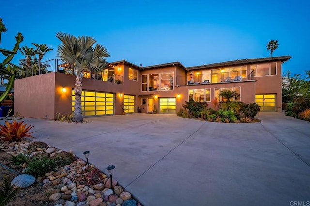 view of front of house featuring a garage, driveway, a balcony, and stucco siding