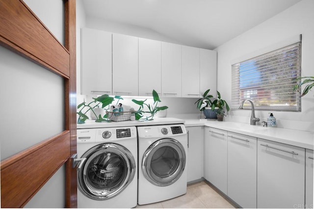 washroom featuring cabinet space, independent washer and dryer, light tile patterned floors, and a sink