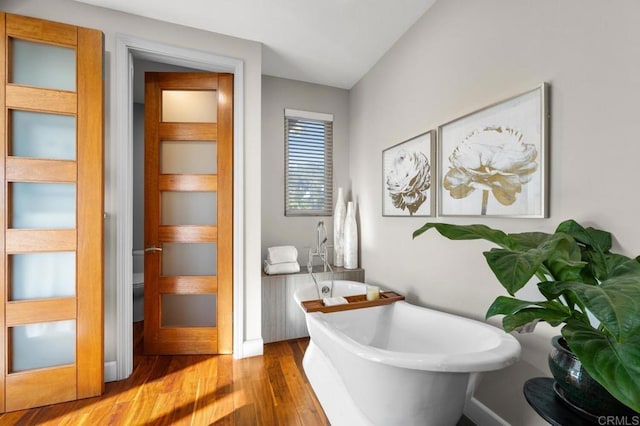 bathroom featuring a soaking tub and wood finished floors