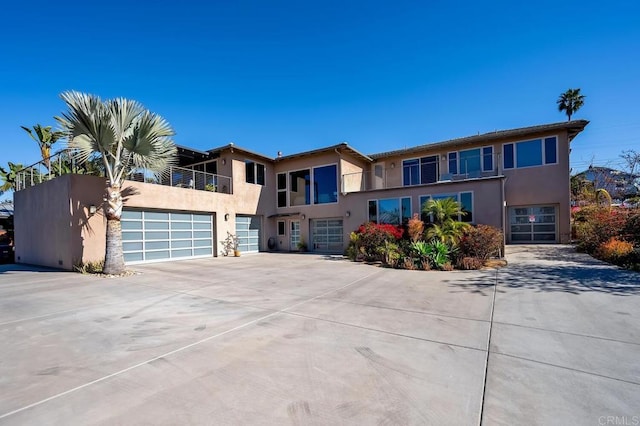 view of front of home featuring stucco siding, an attached garage, driveway, and a balcony
