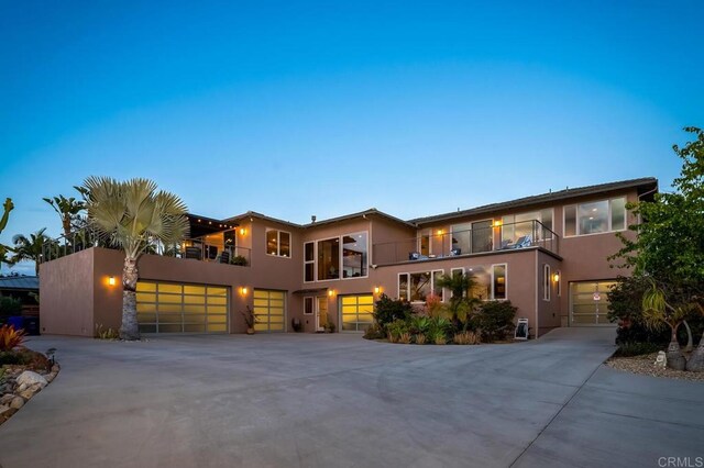 mediterranean / spanish-style house featuring stucco siding, a balcony, and concrete driveway