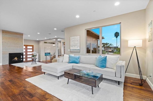 living area featuring baseboards, recessed lighting, wood finished floors, and a large fireplace