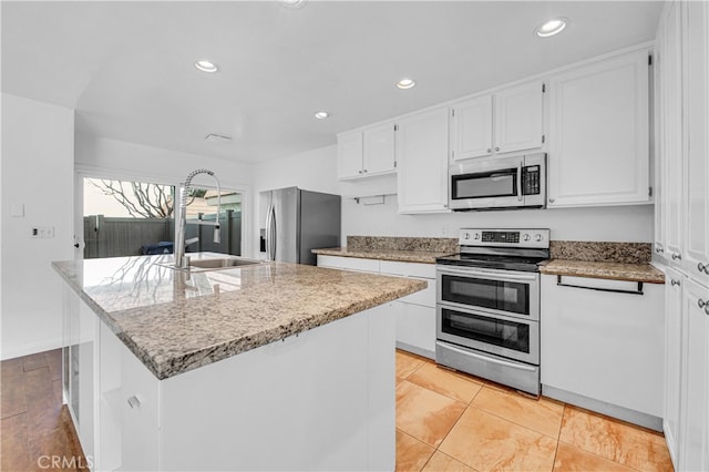 kitchen featuring appliances with stainless steel finishes, a kitchen island with sink, white cabinetry, and light stone countertops