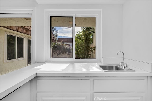 kitchen featuring light countertops, a sink, and white cabinets