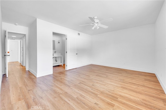 interior space with visible vents, a ceiling fan, a sink, light wood-type flooring, and baseboards