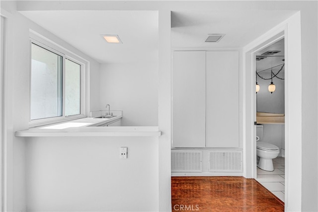 bathroom with toilet, visible vents, a sink, and wood finished floors