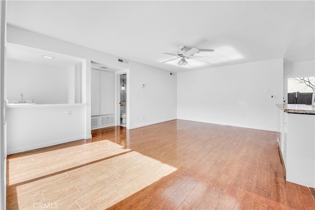 unfurnished living room featuring ceiling fan, wood finished floors, visible vents, and baseboards