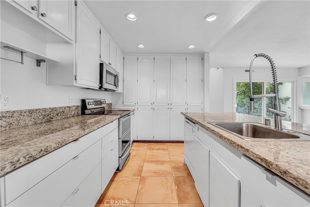 kitchen featuring appliances with stainless steel finishes, light stone countertops, white cabinetry, a sink, and recessed lighting