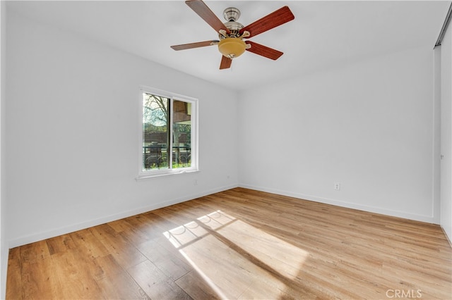 empty room featuring ceiling fan, light wood-style flooring, and baseboards