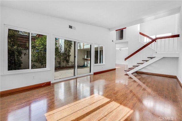 unfurnished living room featuring wood-type flooring, visible vents, and baseboards