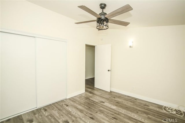 unfurnished bedroom with ceiling fan, a closet, wood finished floors, and baseboards