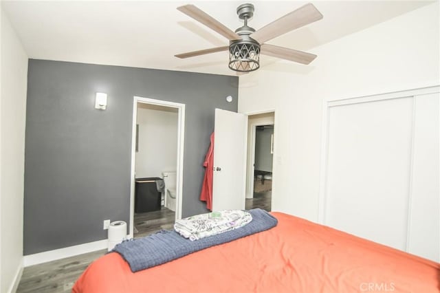 bedroom featuring ceiling fan, wood finished floors, baseboards, a closet, and ensuite bath