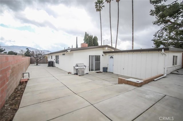 rear view of house featuring a patio, a chimney, a fenced backyard, and a mountain view