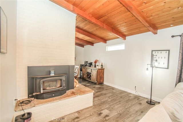 living room with baseboards, wooden ceiling, wood finished floors, a wood stove, and vaulted ceiling with beams