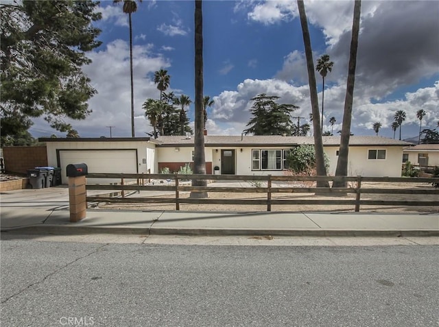 single story home featuring concrete driveway, a fenced front yard, and an attached garage