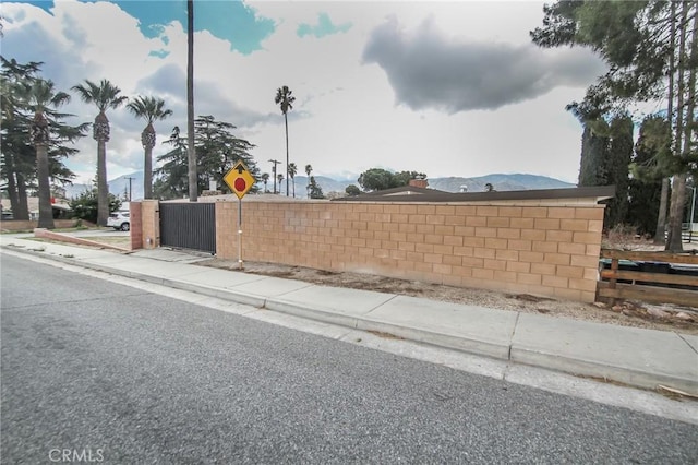 view of street featuring traffic signs, a gate, curbs, and sidewalks