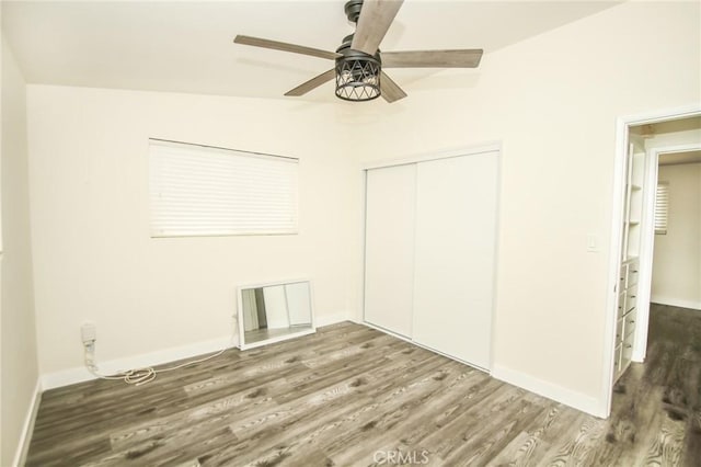 unfurnished bedroom with a ceiling fan, a closet, baseboards, and wood finished floors