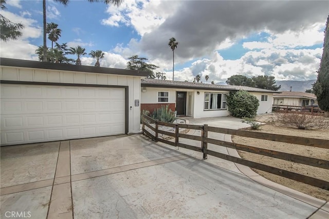 ranch-style home with driveway, a garage, a fenced front yard, board and batten siding, and brick siding