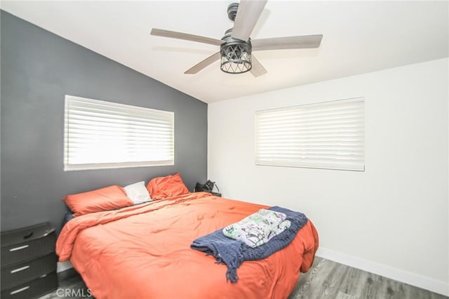 bedroom featuring lofted ceiling, ceiling fan, wood finished floors, and baseboards