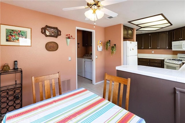 dining space with visible vents, ceiling fan, washing machine and clothes dryer, and light tile patterned floors