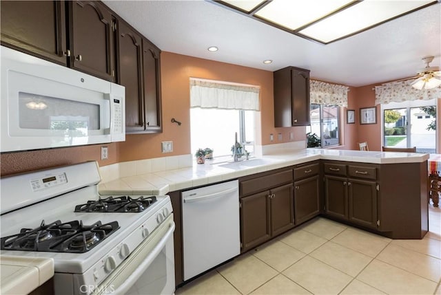 kitchen with tile counters, white appliances, and dark brown cabinetry