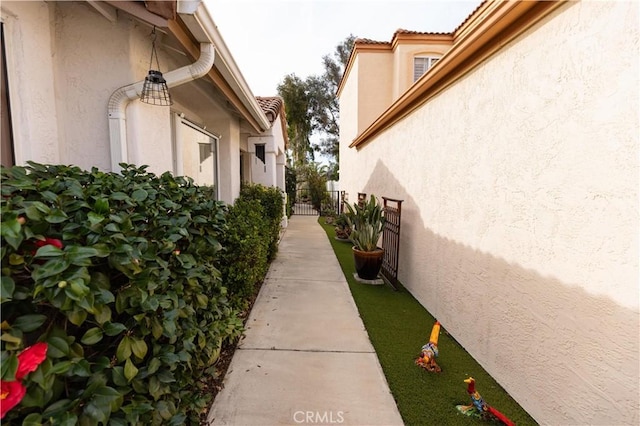 view of side of home featuring fence and stucco siding